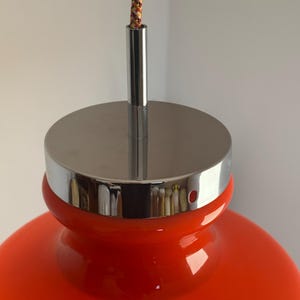 May include: A bright orange glass pendant light with a chrome top and a braided cord.