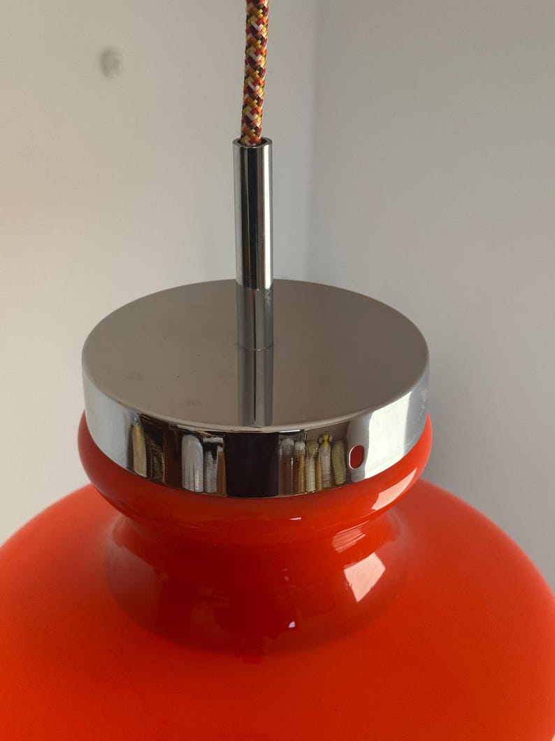 May include: A bright orange glass pendant light with a chrome top and a braided cord.