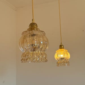 May include: Two gold pendant lights with clear glass shades. The shades have a textured, ribbed design.