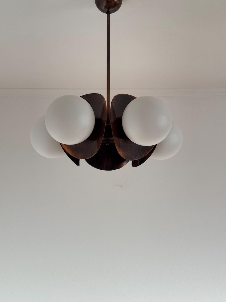 May include: A brown, wooden, flower-shaped chandelier with five white globe light bulbs.
