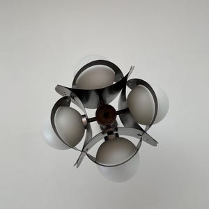 Puede incluir: Una l&aacute;mpara de ara&ntilde;a moderna de tono plateado con cinco globos de vidrio blanco esmerilado. La l&aacute;mpara de ara&ntilde;a tiene un dise&ntilde;o geom&eacute;trico con brazos de metal curvos.