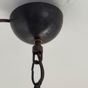 Puede incluir: Primer plano de una l&aacute;mpara de techo de metal negro con una cadena que cuelga. La l&aacute;mpara tiene un acabado texturizado y un tornillo de color lat&oacute;n.