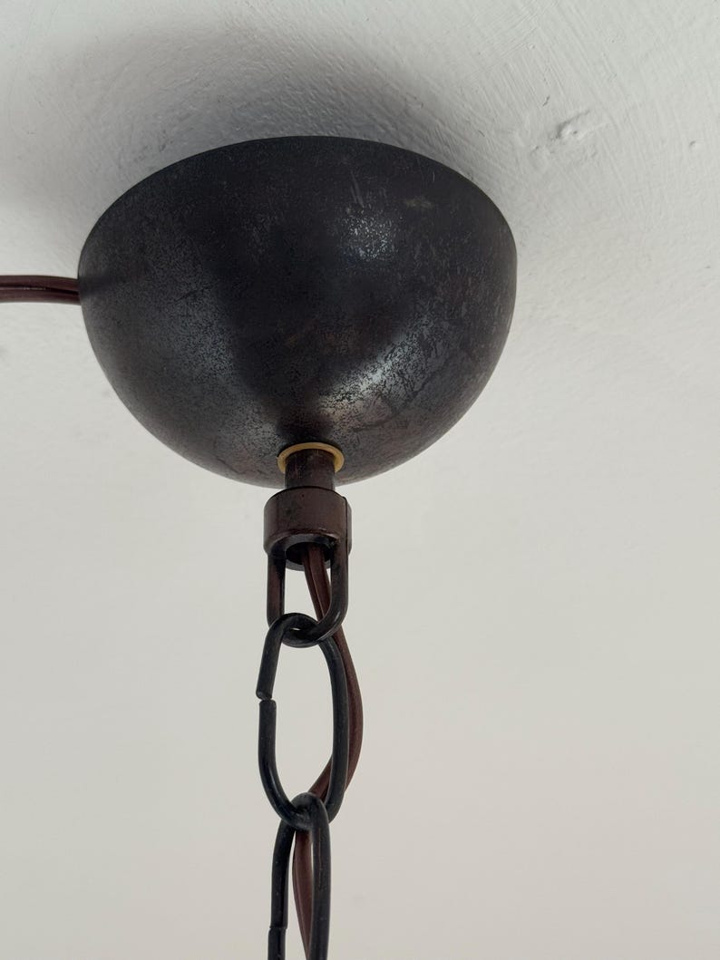 Puede incluir: Primer plano de una l&aacute;mpara de techo de metal negro con una cadena que cuelga. La l&aacute;mpara tiene un acabado texturizado y un tornillo de color lat&oacute;n.