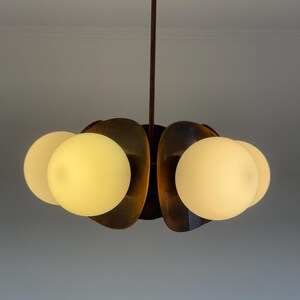 May include: A modern, mid-century style chandelier with five frosted glass globes and a bronze finish.