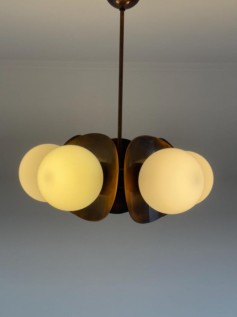 May include: A modern, mid-century style chandelier with five frosted glass globes and a bronze finish.
