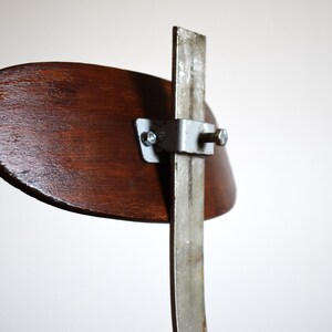 Puede incluir: Un respaldo de silla de madera con un marco de metal y un soporte de metal plateado. El respaldo de la silla es marr&oacute;n y el marco de metal es plateado.