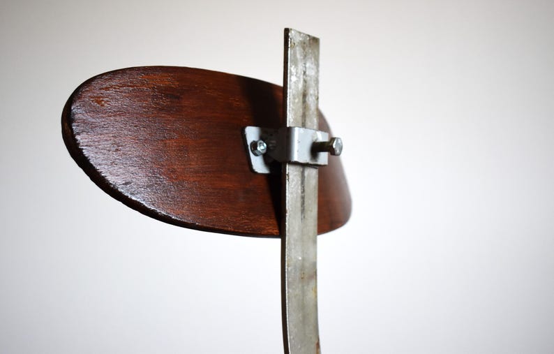Puede incluir: Un respaldo de silla de madera con un marco de metal y un soporte de metal plateado. El respaldo de la silla es marr&oacute;n y el marco de metal es plateado.