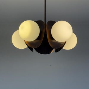 May include: A black metal chandelier with five white globe-shaped light bulbs. The chandelier has a unique design with curved arms that resemble petals.