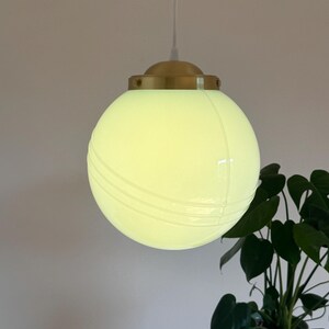 May include: A white globe pendant light with a brass fixture and a white cord. The globe has a subtle ribbed design.