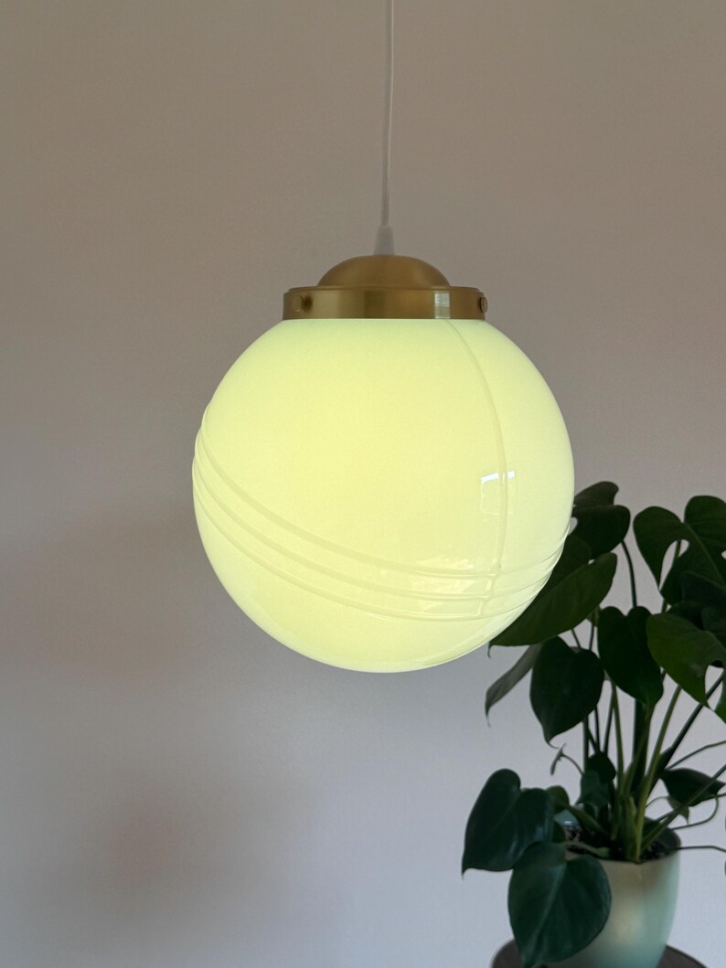 May include: A white globe pendant light with a brass fixture and a white cord. The globe has a subtle ribbed design.