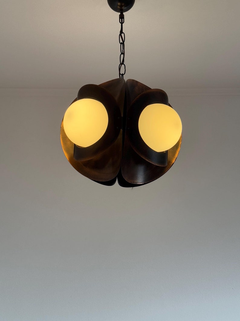 Puede incluir: Una l&aacute;mpara colgante de estilo moderno de mediados de siglo con un acabado marr&oacute;n oscuro de madera. La l&aacute;mpara tiene dos bombillas blancas en forma de globo.