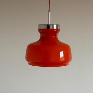 May include: A bright orange glass pendant light with a chrome finish and a brown cord.