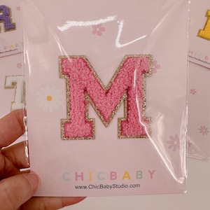 May include: Pink felt letter M with gold glitter trim, packaged on a pink card with white daisies and the text "CHICBABY www.ChicBabyStudio.com"
