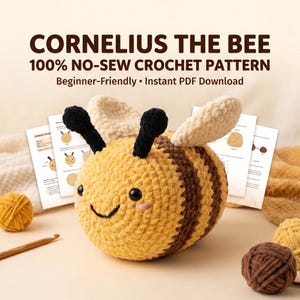 Peut inclure: Une peluche abeille au crochet avec des rayures jaunes et brunes, des antennes noires et des ailes couleur crème. L'abeille a des yeux de sécurité noirs et un sourire brodé. Derrière, des pages imprimées titrées CORNELIUS THE BEE 100% NO-SEW CROCHET PATTERN.