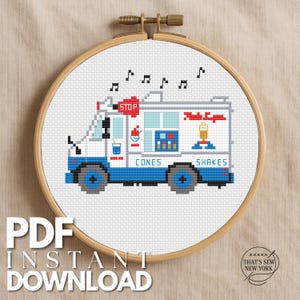 May include: A cross-stitch pattern in a wooden embroidery hoop featuring a white ice cream truck with blue accents, a red stop sign, and the text CONES and SHAKES. Musical notes float above the truck, which displays colorful food graphics.