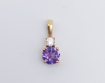 May include: A gold pendant with a purple amethyst gemstone and a smaller clear diamond accent.