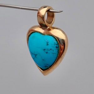 May include: A gold heart-shaped pendant with a turquoise stone set in the center.