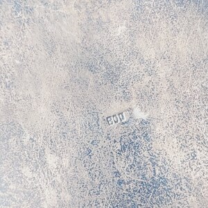 May include: Close-up of a silver-colored surface with a worn, textured finish. The surface has a faint inscription of "800" in the lower right corner.