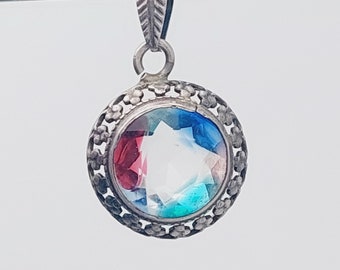 May include: A silver pendant with a round, multi-colored gemstone set in a filigree frame.