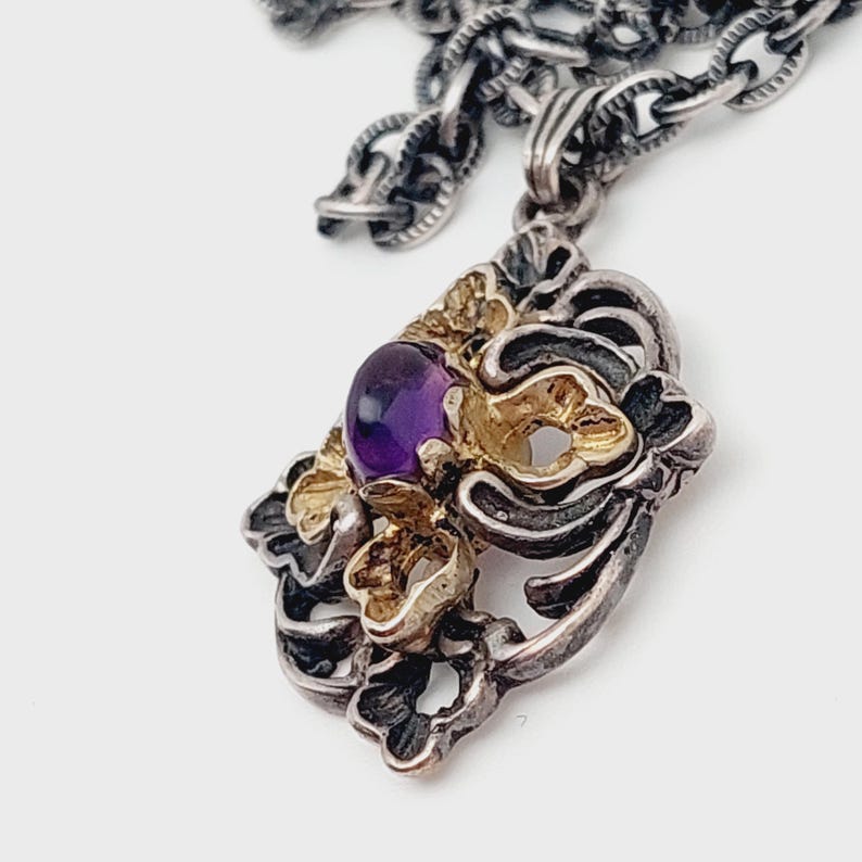 Puede incluir: Un collar con un colgante de plata y oro con una amatista engastada en un dise&ntilde;o floral.