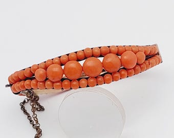 May include: A vintage coral bracelet with a gold clasp and a chain. The bracelet is made of three rows of coral beads, with larger coral beads in the center row.