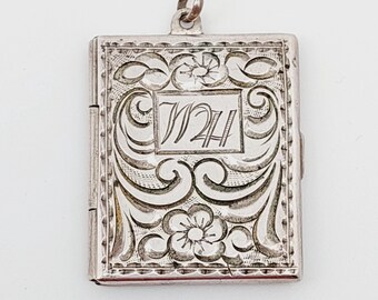 May include: Silver locket with an engraved floral design and the initials "WH" in the center.