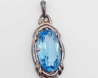 May include: A silver pendant with a blue gemstone set in a silver and gold frame.