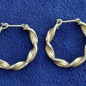 Puede incluir: Un par de pendientes de aro de oro con un dise&ntilde;o trenzado. Los pendientes est&aacute;n hechos de dos tonos de oro diferentes, creando un look &uacute;nico y elegante.