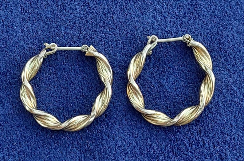 Puede incluir: Un par de pendientes de aro de oro con un dise&ntilde;o trenzado. Los pendientes est&aacute;n hechos de dos tonos de oro diferentes, creando un look &uacute;nico y elegante.