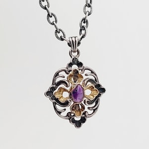 Puede incluir: Un collar de cadena de plata con un colgante que presenta una piedra preciosa p&uacute;rpura engastada en un dise&ntilde;o de filigrana de oro y plata.