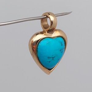 May include: A gold heart-shaped pendant with a turquoise stone set in the center.