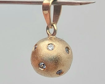 May include: A gold pendant with a textured sphere shape and small clear gemstones set into the surface.