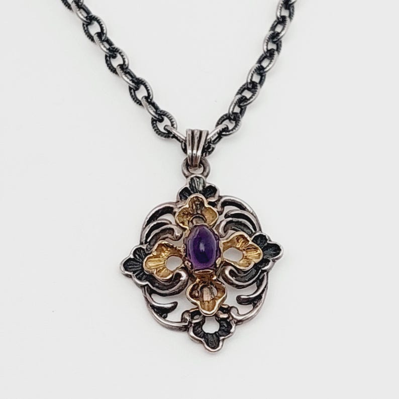 Puede incluir: Un collar de cadena de plata con un colgante que presenta una piedra preciosa p&uacute;rpura engastada en un dise&ntilde;o de filigrana de oro y plata.