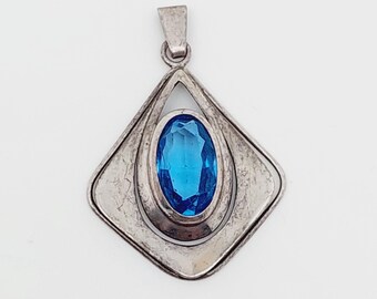 May include: A silver pendant with a blue gemstone set in a geometric design.