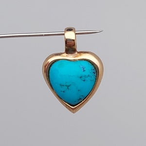 May include: A gold heart-shaped pendant with a turquoise stone set in the center.