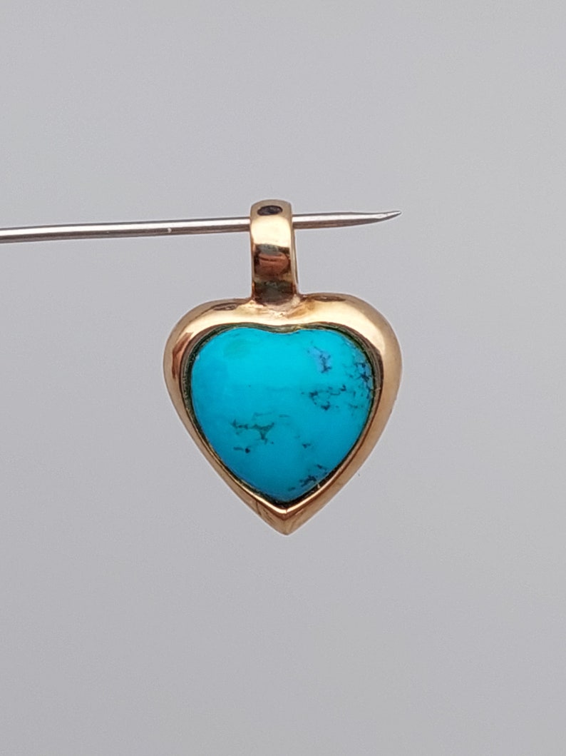 May include: A gold heart-shaped pendant with a turquoise stone set in the center.