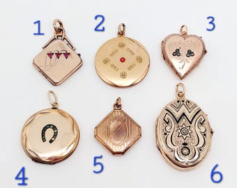 May include: Six antique gold locket pendants with various designs. The lockets are numbered 1 through 6. Locket 1 is a square with a red flower design. Locket 2 is round with a red stone in the centre. Locket 3 is heart-shaped with a black floral design. Locket 4 is round with a horseshoe design. Locket 5 is a hexagon with a striped design. Locket 6 is oval with a black and white floral design.