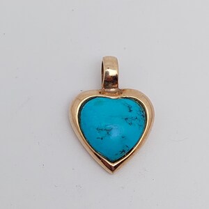 May include: A gold heart-shaped pendant with a turquoise stone set in the center.