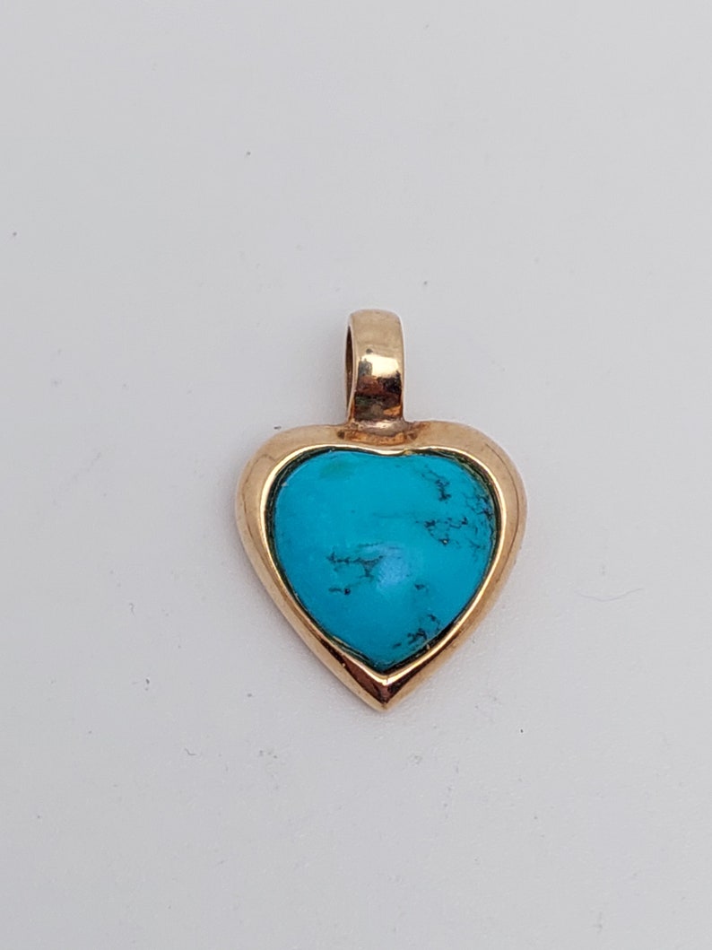 May include: A gold heart-shaped pendant with a turquoise stone set in the center.
