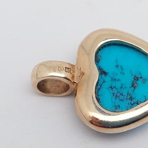 May include: Gold heart-shaped pendant with a turquoise stone set in the center. The pendant has a bail for attaching to a chain.