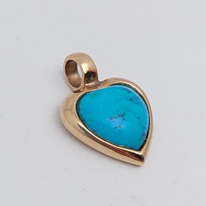 May include: A gold heart-shaped pendant with a turquoise stone set in the center.