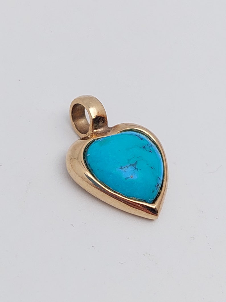 May include: A gold heart-shaped pendant with a turquoise stone set in the center.