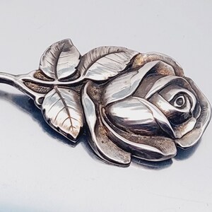 May include: A silver rose brooch with detailed leaves and a textured finish.