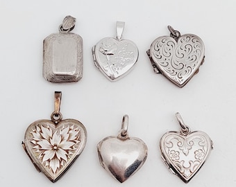 May include: Six silver locket pendants, including a rectangular locket and five heart-shaped lockets. Some of the lockets have engraved designs, including a flower and a bird.