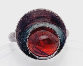 Op de afbeelding: Een zilveren ring met een rode barnsteen in een cirkelvormig ontwerp.