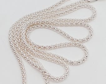 Könnte beinhalten: Eine silberne Halskette mit einer strukturierten, perlenbesetzten Kette. Die Kette besteht aus kleinen, runden Perlen, die eine strukturierte Oberfläche erzeugen. Die Halskette hat einen Karabinerverschluss.