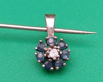 May include: A silver pendant with a flower design featuring a central white gemstone surrounded by blue gemstones.