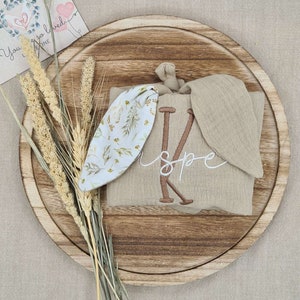 Beige comforter with bunny ears, featuring floral pattern and embroidered baby name
