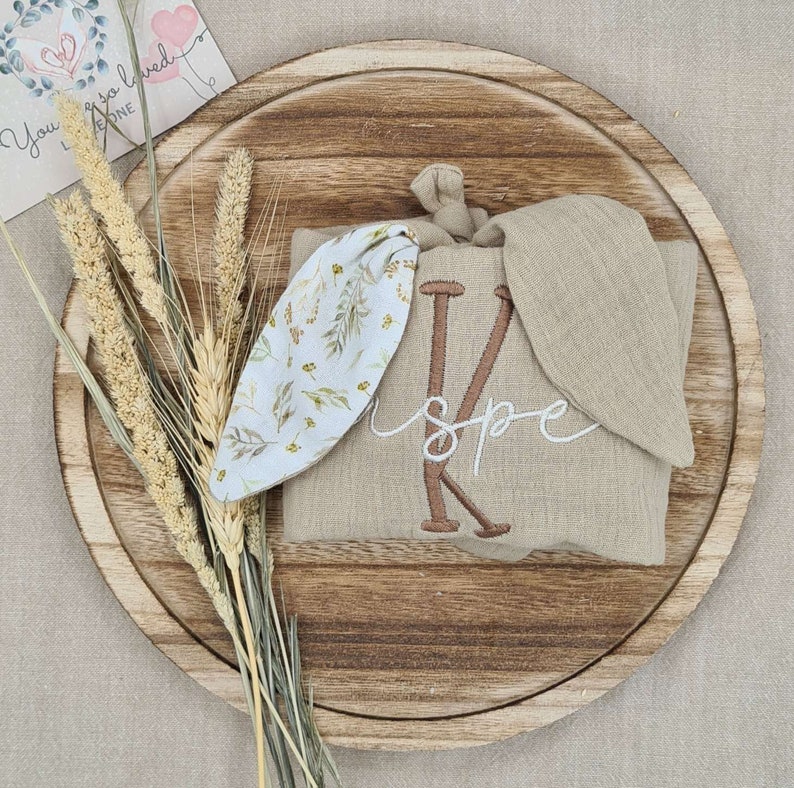 Beige comforter with bunny ears, featuring floral pattern and embroidered baby name
