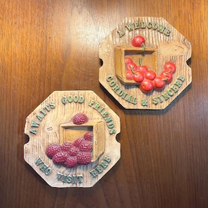 May include: Two wooden wall plaques with octagonal shapes. One features red cherries and the text "A WELCOME CORDIAL & SINCERE". The other has raspberries and reads "AWAITS GOOD FRIENDS WHO VISIT HERE".